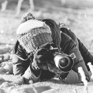 Alexandra Wagner liegt mit winterlicher Kleidung im Schnee und fotografiert