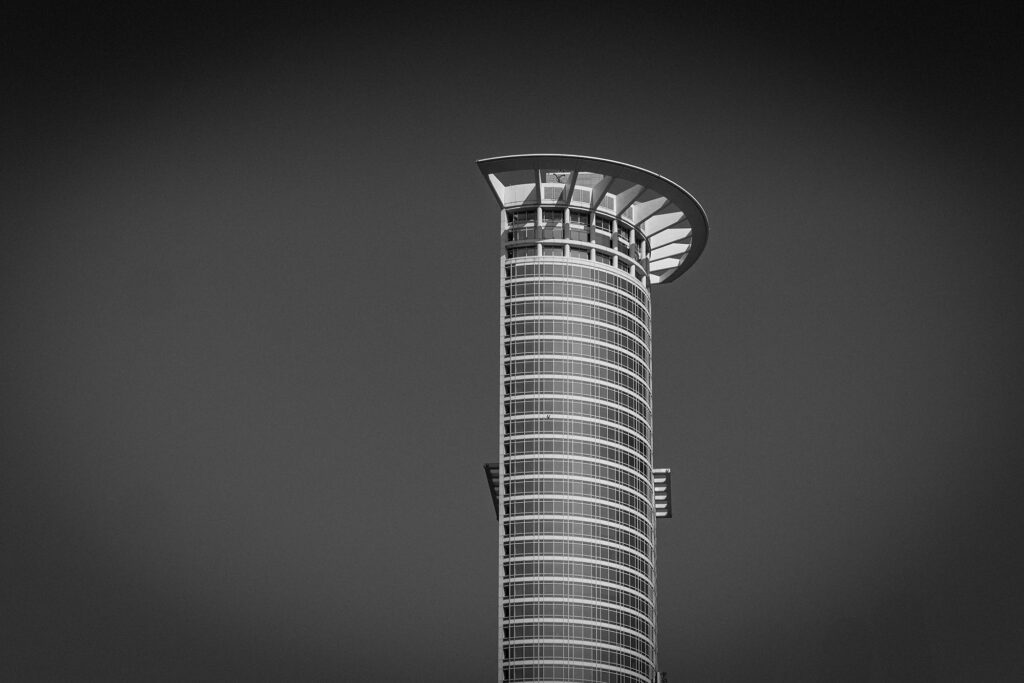 Schwarzweißaufnahme des oberen Teils der DZ Bank in Frankfurt mit klarer Linienführung und modernem Design.