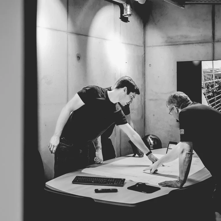 Einblick in die Arbeitswelt der Metallverarbeitung: Schweißen, Bürosituationen und Mitarbeiterporträts in Schwarz-Weiß.