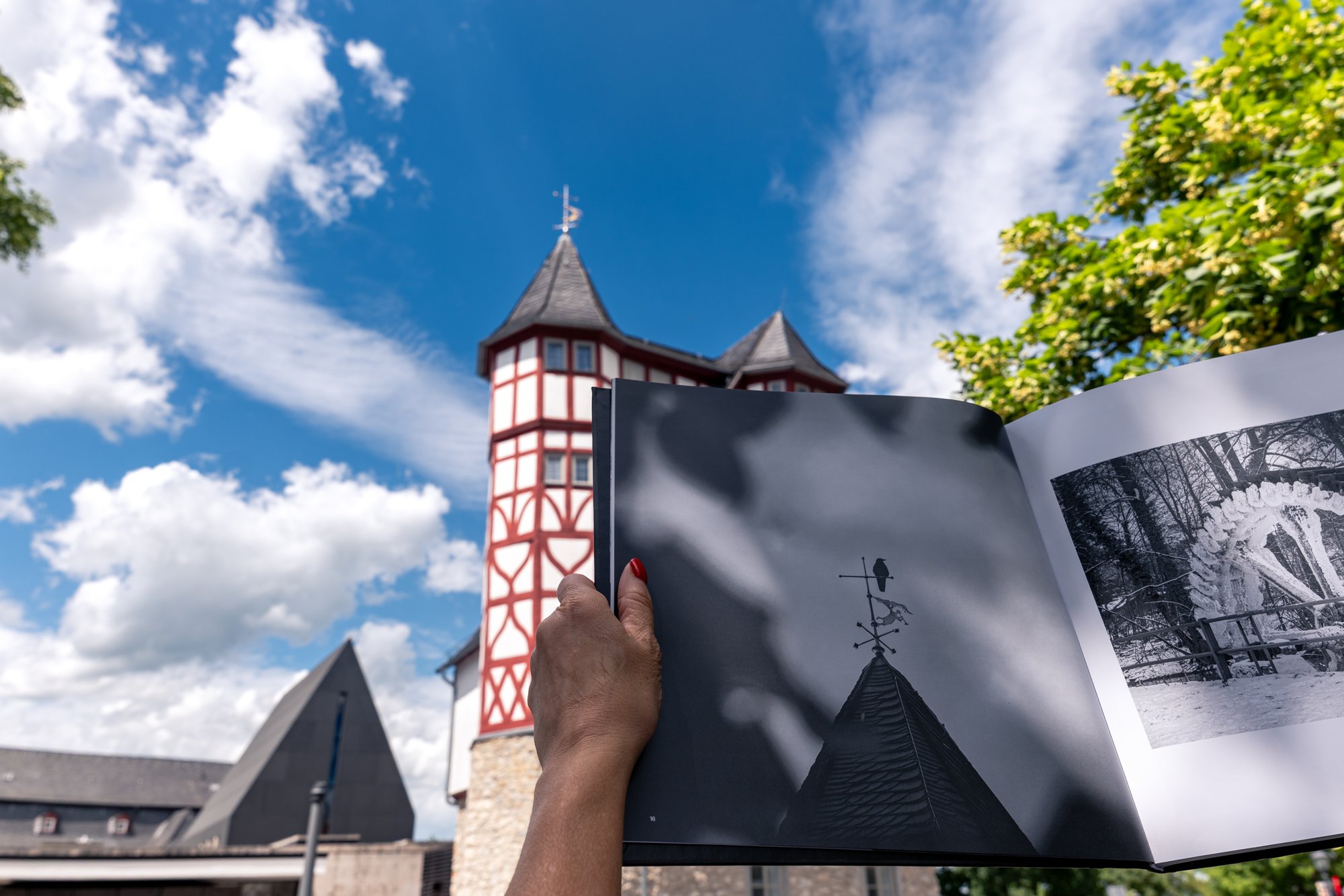 Aufgeschlagener Bildband mit Schwarzweißfoto einer Wetterfahne vor dem echten Fachwerkturm in Limburg