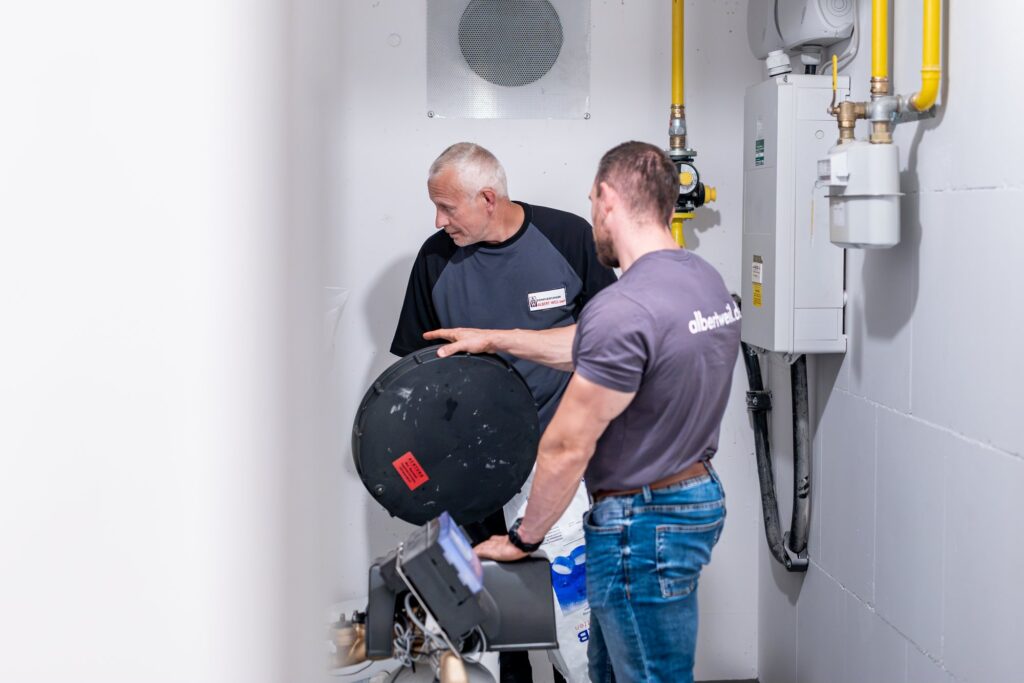 Zwei Facility-Management-Mitarbeiter kontrollieren gemeinsam die Heizungsanlage