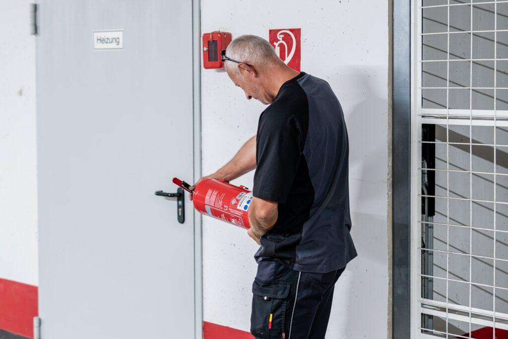 Hausmeister prüft einen Feuerlöscher an der Kellertür