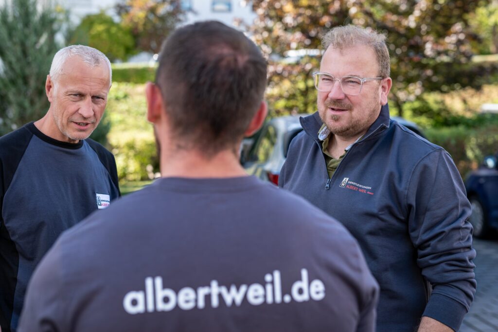 Drei Mitarbeiter der Dienstleistungen Albert Weil GmbH im Gespräch vor dem Gebäude