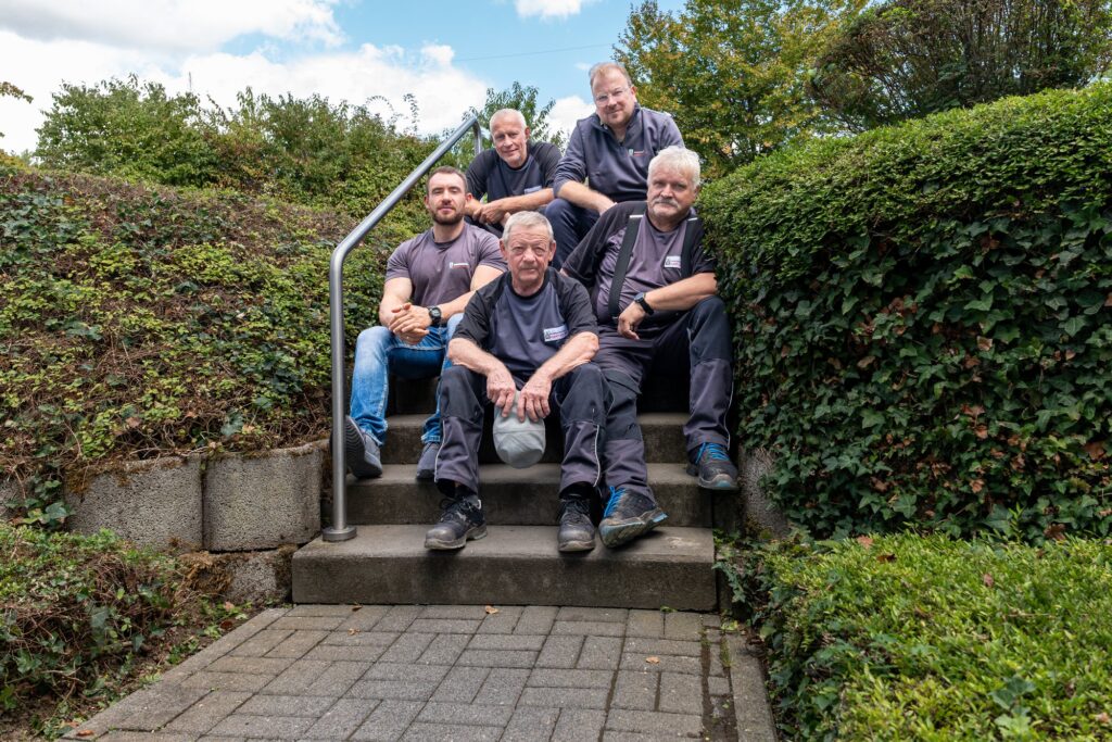 Team der Dienstleistungen Albert Weil GmbH sitzt gemeinsam auf einer Außentreppe