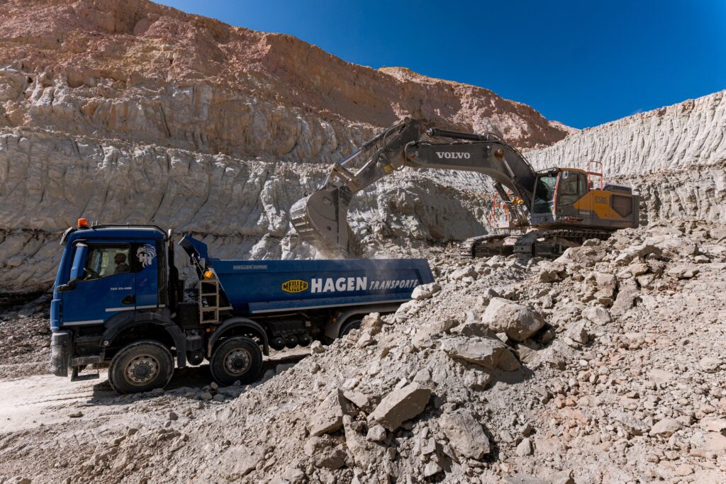 Lkw und Bagger vor einer hellen Tonwand