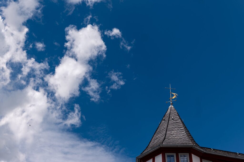 Turmspitze mit Wetterfahne in Limburg vor blauem Himmel